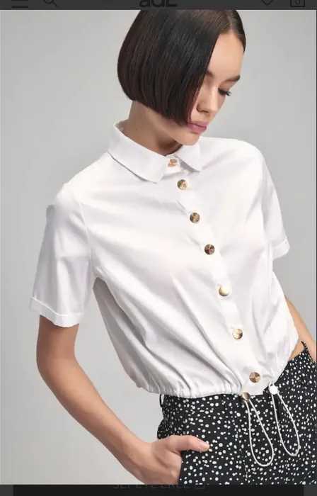 White womenswear polo top with decorative buttons